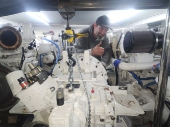 Technician deep in an engine bay — twin inboard service